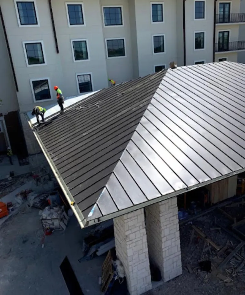 Crew installing standing seam metal roof panels on a commercial project in Roy